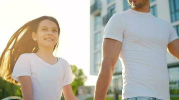 papà e figlia camminare in giro loro la zona a tramonto. bambino detiene Il padre di mano video