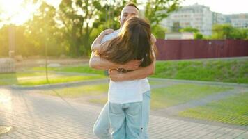 Daughter runs to dad and hugs him. Father picks up the child in his arms. Slow motion video