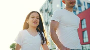 papá y hija caminar alrededor su zona a puesta de sol. niño sostiene del padre mano video