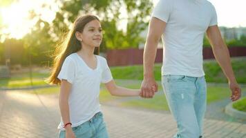 Dad and daughter walk around their area at sunset. Child holds father's hand video