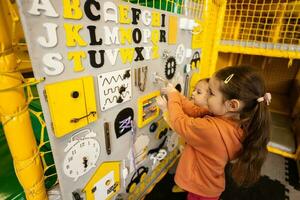 Two sisters playing with busy board at kids play center. photo