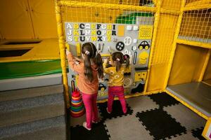 dos hermanas jugando con ocupado tablero a niños jugar centro. foto