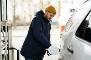 hombre repostando su camión suv americano en la gasolinera cuando hace frío. foto