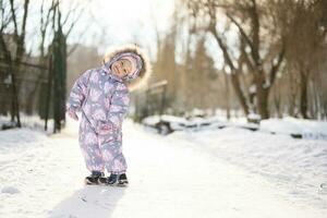 Baby girl wear child snowsuit on a sunny frosty winter day. photo