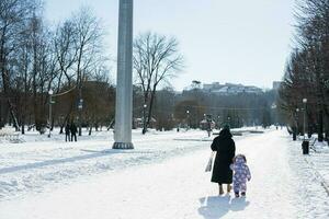 Back view of mother and child walking on a sunny frosty winter day in the park. photo