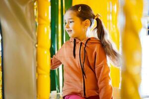 Little girl kid slide at yellow playground park. Child in active entertaiments. photo