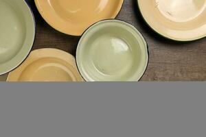 Enamel tin metal food plate pot bowl retro vintage tableware dinnerware on rustic wood background top view photo