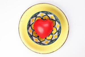 ceramic decorated food bowl yellow plate with three dimension 3d red hart symbol inside on white background copy text space top view photo