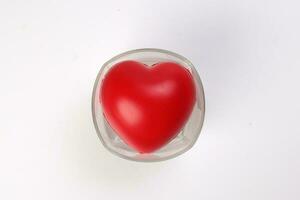 transparent drink glass with three dimension 3d red hart symbol inside on white background copy text space top view photo
