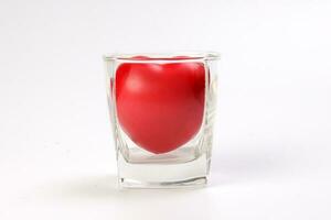 transparent drink glass with three dimension 3d red hart symbol inside on white background copy text space photo