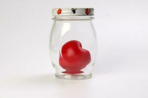 transparent glass jar with lid with three dimension 3d red hart symbol inside on white background copy text space photo