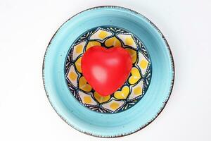 ceramic decorated food bowl blue plate with three dimension 3d red hart symbol inside on white background copy text space top view photo