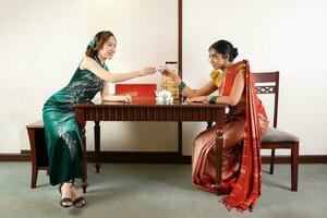 Beautiful young woman wearing traditional cultural dress of Malaysia malay Indian Chinese saree cheongsam talk pose retro vintage look table photo