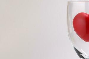 transparent wine glass with three dimension 3d red hart symbol inside on white background copy text space photo