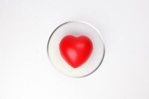 transparent glass bowl with three dimension 3d red hart shape symbol inside on white background copy text space top view photo