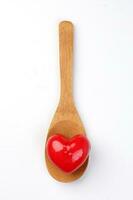 small three dimension 3d red hart shape symbol on top of wooden spoon on white background photo
