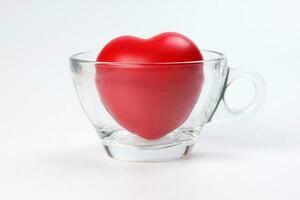 transparent glass coffee tea cup saucer with three dimension 3d red hart symbol inside on white background copy text space photo