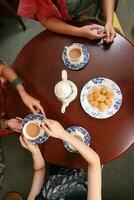 Top view of tea drink party woman hands pouring sharing teapot teacup saucer traditional biscuit Asian dress photo