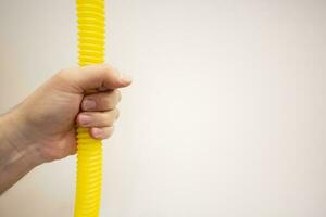Hands holding a yellow hose on a white background close-up photo