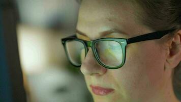 Woman in glasses looking on the monitor and and working with charts and analytics. The monitor screen is reflected in the glasses. video