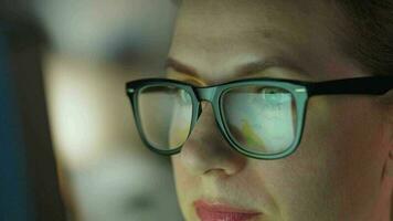 Woman in glasses looking on the monitor and and working with charts and analytics. The monitor screen is reflected in the glasses. video