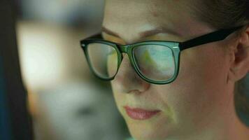 Woman in glasses looking on the monitor and and working with charts and analytics. The monitor screen is reflected in the glasses. video