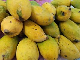 Fresh colorful tropical mangoes on display at outdoor farmers market photo