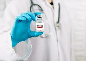 Doctor holding vaccine bottle coronavirus and medical in the hospital photo