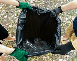 Human hand collect plastic waste in trash bags for the environment photo