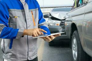 Insurance officer writing clipboard and examining check for damage car after accident. photo