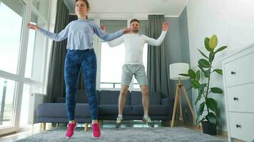 Caucasian couple is doing cardio exercise at home in cozy bright room, slow motion video