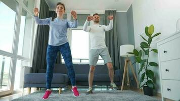 caucasiano casal é fazendo cardio exercício às casa dentro acolhedor brilhante sala, lento movimento video