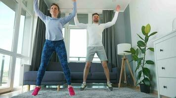 Caucasian couple is doing cardio exercise at home in cozy bright room, slow motion video