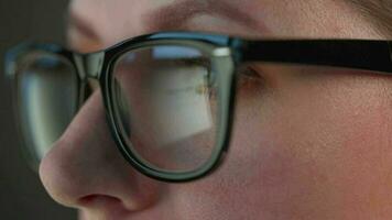 Woman in glasses looking on the monitor and and working with charts and analytics. The monitor screen is reflected in the glasses. video