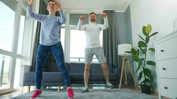 Caucasian couple is doing cardio exercise at home in cozy bright room, slow motion video