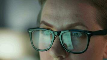 Woman in glasses looking on the monitor and and working with charts and analytics. The monitor screen is reflected in the glasses. video