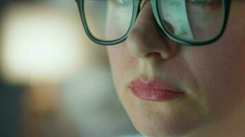 mujer en lentes mirando en el monitor y y trabajando con cartas y analítica. el monitor pantalla es reflejado en el lentes. video