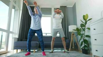 Caucasian couple is doing cardio exercise at home in cozy bright room, slow motion video