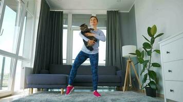 Woman squats with a cat in her arms, slow motion. Home workouts video