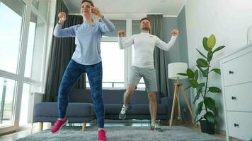 caucasiano casal é fazendo cardio exercício às casa dentro acolhedor brilhante sala, lento movimento video