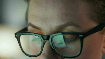 Woman in glasses looking on the monitor and and working with charts and analytics. The monitor screen is reflected in the glasses. video