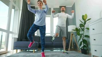 Caucasian couple is doing cardio exercise at home in cozy bright room, slow motion video