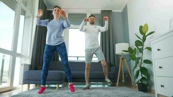 caucasiano casal é fazendo cardio exercício às casa dentro acolhedor brilhante sala, lento movimento video