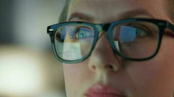 mujer en lentes mirando en el monitor y y trabajando con cartas y analítica. el monitor pantalla es reflejado en el lentes. video