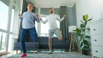 Caucasian couple is doing cardio exercise at home in cozy bright room, slow motion video