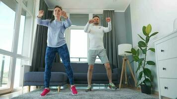 Caucasian couple is doing cardio exercise at home in cozy bright room, slow motion video