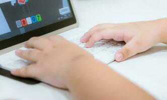 child's hand on computer keyboard play a game photo