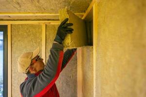 Contractor Installing Mineral Wool Inside Garden Shed Walls. photo