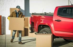 Professional Mover Carrying Cardboard Box to His Car photo