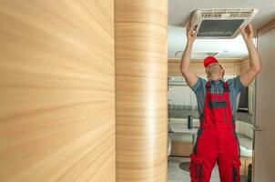 RV Service Worker Replacing or Fixing Travel Trailer Air Condition photo